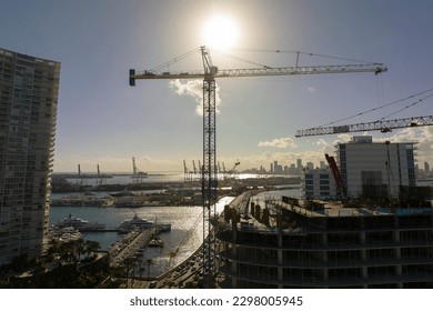 New construction site of developing residense in american urban area. Industrial tower lifting cranes in Miami, Florida. Concept of housing growth in the USA