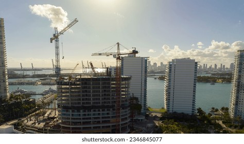 New construction site of developing residense in american urban area. Industrial tower lifting cranes in Miami, Florida. Concept of housing growth in the USA