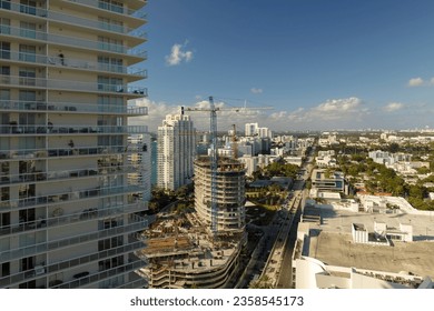 New construction site of developing residense in american urban area. Industrial tower lifting cranes in Miami, Florida. Concept of housing growth in the USA