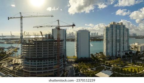 New construction site of developing residense in american urban area. Industrial tower lifting cranes in Miami, Florida. Concept of housing growth in the USA