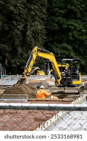 New construction started in a mixed use commercial and industrial zone, cleared job site with foundation started, heavy equipment and workers behind chain-link fence
