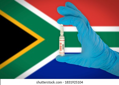 New Coronavirus Vaccine With The Flag Of South Africa In The Background. South Africa Medical Research And Vaccine Development Center. Doctor Holding Coronavirus Vaccine In His Hand.