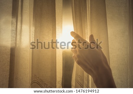 New day and new beginnings, rise and shine concept. Hand opening up window curtain letting the early morning sunshine in.  ストックフォト © 