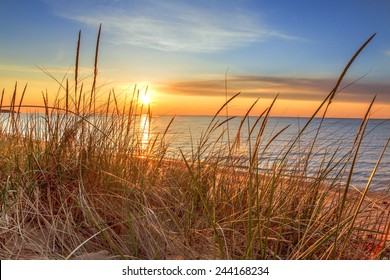 New Day Dawns. The sunrises over the horizon, illuminating the dune grass and beach.