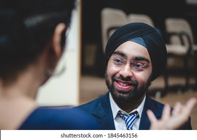 New Delhi, Delhi, India - 12/05/2014: A happy smiling Indian student wearing a black turban discussing with teacher after class. A man in formal wear talking to professor to understand the lecture.