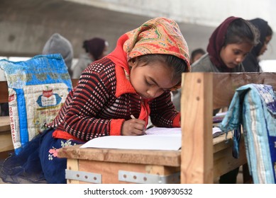 NEW DELHI, INDIA - 16 JANUARY 2021. Underprivileged Children Study At An Improvised Classroom Set Up Under A Construction Of A Metro Train Bridge In A Foggy Winter Morning In New Delhi.