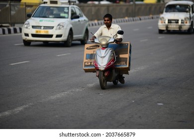 New Delhi, India- Aug 23 2019: Delhi Typical Street Scene Of Man Transporting New Big Screen Color Tv On Electric Bike In Motion