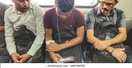 New Delhi, India - August 23 2019: Two Passengers Looking Into A Third Person's Mobile Phone While Travelling In Delhi Metro.