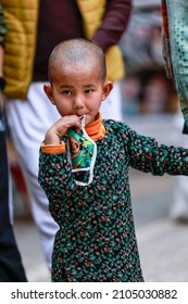 New Delhi, India - December 2021: Portrait of young Indian tibetan kid  having drink at the monastery area.