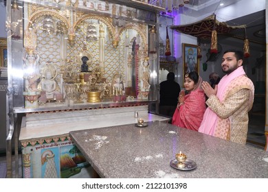 New Delhi, India - Feb 07 2020: A Newly Wedded Couple Praying In Jain Temple Asking The Blessings From The God. Indian Groom Dressed In Ivory Sherwani And Stunning Bride Pink Lehenga. Indian Wedding.