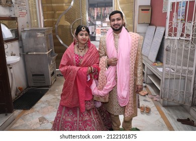 New Delhi, India - Feb 07 2020: A Newly Wedded Couple Praying In Jain Temple Asking The Blessings From The God. Indian Groom Dressed In Ivory Sherwani And Stunning Bride Pink Lehenga. Indian Wedding.