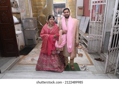 New Delhi, India - Feb 07 2020: A Newly Wedded Couple Praying In Jain Temple Asking The Blessings From The God. Indian Groom Dressed In Ivory Sherwani And Stunning Bride Pink Lehenga. Indian Wedding.