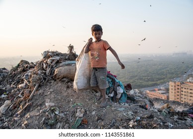 New Delhi, India - July 25, 2018: A poor boy collecting garbage waste from a landfill site in the outskirts of Delhi. Hundreds of children work at these sites to earn their livelihood.