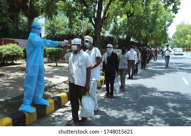 NEW DELHI, INDIA - June 02, 2020: A Health Worker Wearing PPE Kit As He Check Thermal Temperature Of Labor Before Collect Food In The Lockdown