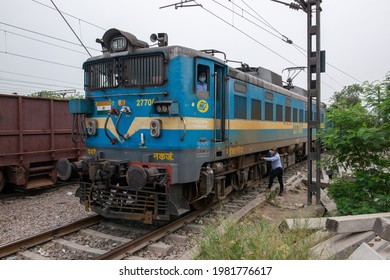 New Delhi, India, May 18 2021: Feight Train Engine Driver With Mask Looking Out From Electric Engine Car, Feight Train Parked On Loop Line