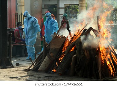 NEW DELHI, INDIA - May 30, 2020: COVID 19 Death In Indian, Health Workers Wearing Personal Protective Equipment Relatives Carrying The Mortal Remains Of A COVID-19 Victim At The Crematorium