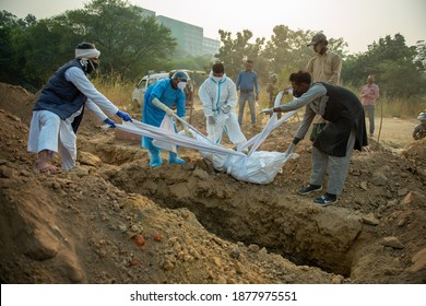 New Delhi, India -November 5 2020: Graveyard Caretaker And Waqf Board Member Lowering A Dead Body In Burial Who Died Of Covid-19. 