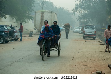 New Delhi, India- November 9 2020:  A Rickshaw Puller Carrying Passenger During Delhi Winter