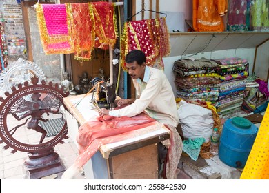 New Delhi, India - October 6 2013: An Indian Craftman Works On A Sari, A Traditional Cloth For Women, In Front Of The Shop In The Streets Of New Delhi, India Capital City.