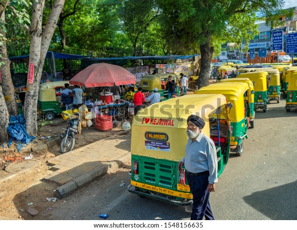 New Delhi / India - September 27, 2019: Sikh man in\
front of Tuk Tuks in the streets of New Delhi, India. Tuk Tuks are\
painted with I Love Kejriwal slogan, campaign of Delhi\'s ruling Aam\
Aadmi Party