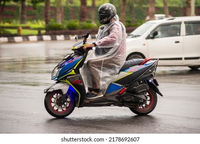 New Delhi, India-13 July 2022: Man Riding Two-wheeler During Rain In Delhi, One Man Put On Raincoat And Motor Cycle, 