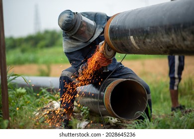 New Delhi, India-Aug 20 2021: Mechanic Using Circular Saw Electric Grinder Tool With Protective Work Wear During Natural Gas Pipeline Construction Work In India, Asian Engineer Operating Industrial Gr