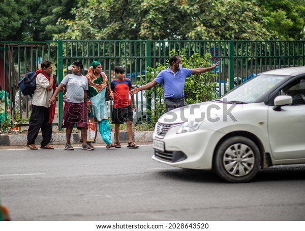 New\
Delhi, India-Aug 20 2021: people crossing road on busy traffic near\
bus terminal anand vihar,  breaking rules people crossing road\
illegally, they are not using foot over\
bridge.