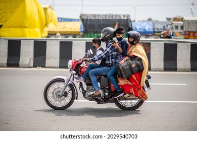 New Delhi, India-Aug 22 2021: Indian family in ethnic wear Travelling on Royal Enfield Bullet during raksha bandhan festival,   Mother, father and small child riding on scooter through busy city stree
