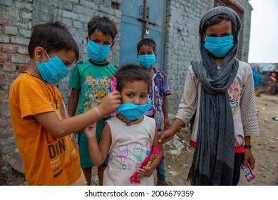 New Delhi, India-July 11 2021: Slum Children helps a kid in New Usmanpur to wear a face mask during the Covid-19 Awareness Campaign in Slum area near new Usmanpur in New Delhi, 