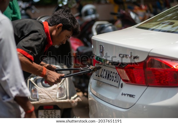 New
Delhi, India-July 31 2021:  A worker seen fixing a high security
registration plates with a tool on a Car, high security number
plate; high security registration plate for
car