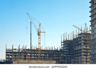 New development. Construction of a residential complex. A construction site with a group of buildings under construction and construction cranes against a blue sky.                               