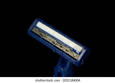 New disposable razor blade with water droplets. Macro shooting
