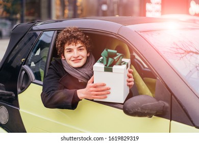 New Driver. Young Curly Caucasian Man Buy First Used Car. Happy Eaxcited Male Teenager Student Holding Box Gift With Green Bow Sitting In His New Car.