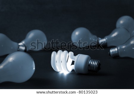 A new energy efficient CFL light bulb shines while the old ones fade into darkness.