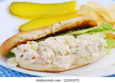 New England Lobster Roll Sandwich With Chips And Pickle Slices On White Plate.