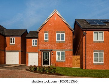 New English Red Brick Build Homes In A Residential Development In Central England, UK. Detached Traditional Houses With Black Door And Garage.