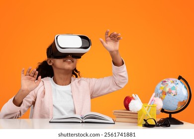 New Experience In Education And Knowledge. Black teenager using modern VR glasses for studying, gesturing on orange yellow studio background, sitting at desk with globe and books, free copy space