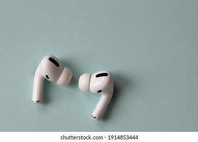 New fashionable white wireless bluetooth headphones on a gray-blue background, close-up, macro, top view. The concept of the use of technology, progress, convenient gadgets, devices. Horizontal.