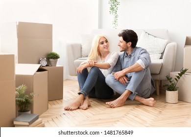 New Flat Owners. Young Couple Relaxing On Floor After Moving In Discussing Future Plans. Empty Space
