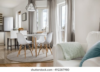 New flat with round table, white chairs and open kitchen
