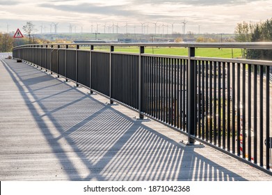 New footbridge with metal railings and a view of windmills