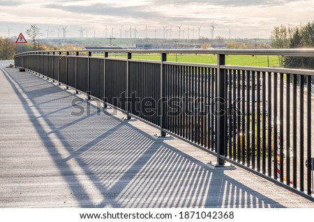 New footbridge with metal railings and a view of windmills