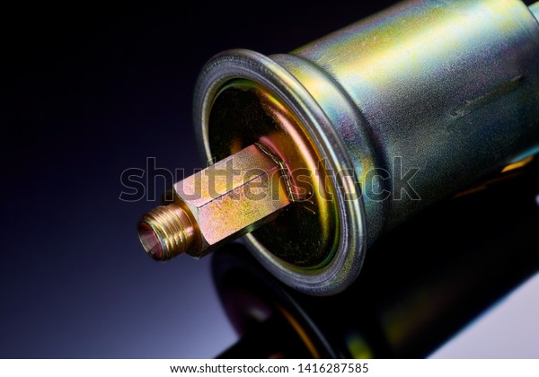 A new fuel filter\
enclosed in a metal casing with an inlet and outlet on fuel lines\
on a dark background