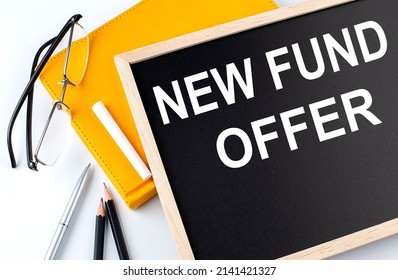 NEW FUND OFFER text on blackboard with notepad , pen, pencil