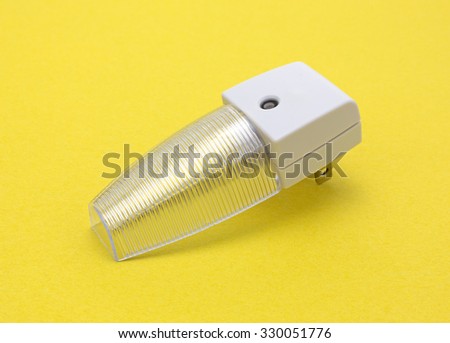 A new generic LED night light that turns on automatically in darkness on a yellow background.
