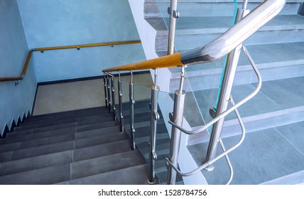 New glass staircase with railing. Modern design, stainless steel, glass and wood are applied when installing fall protection-railing on the stairs.