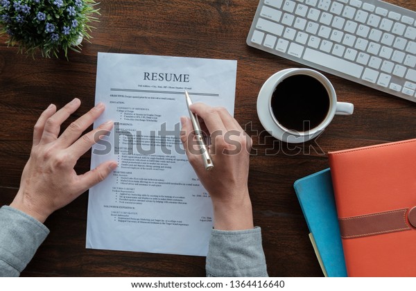 New\
graduate student holding resume application with pen coffee cup\
keyboard and notebook for applying for a\
job.