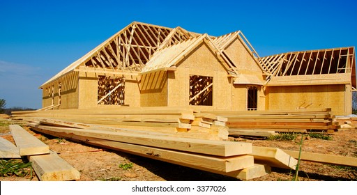 New home under construction with wood, trusses and supplies - Shutterstock ID 3377026