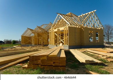 New Home Under Construction With Wood, Trusses And Supplies Against Blue Sky