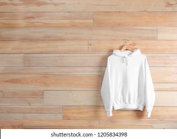 New Hoodie Sweater With Hanger On Wooden Wall. Mockup For Design